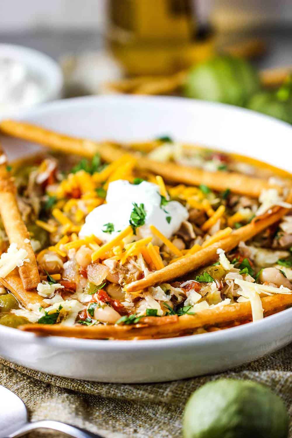 A white bowl of white chili with roasted tomatillos and chicken