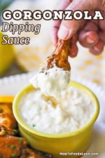 A person holding an Italian-style chicken wing that has been plunged and removed from a yellow bowl of gorgonzola dipping sauce.