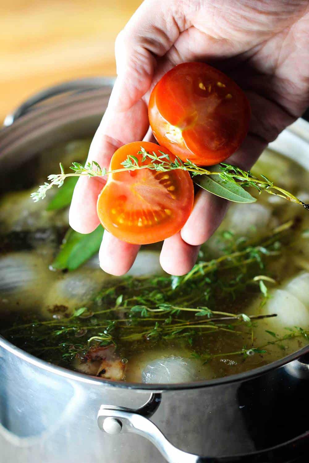 Tomatoes and fresh herbs into the stock pot for homemade beef stock