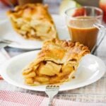 A close-up view of a slice of homemade apple pie next to a glass cup of coffee.