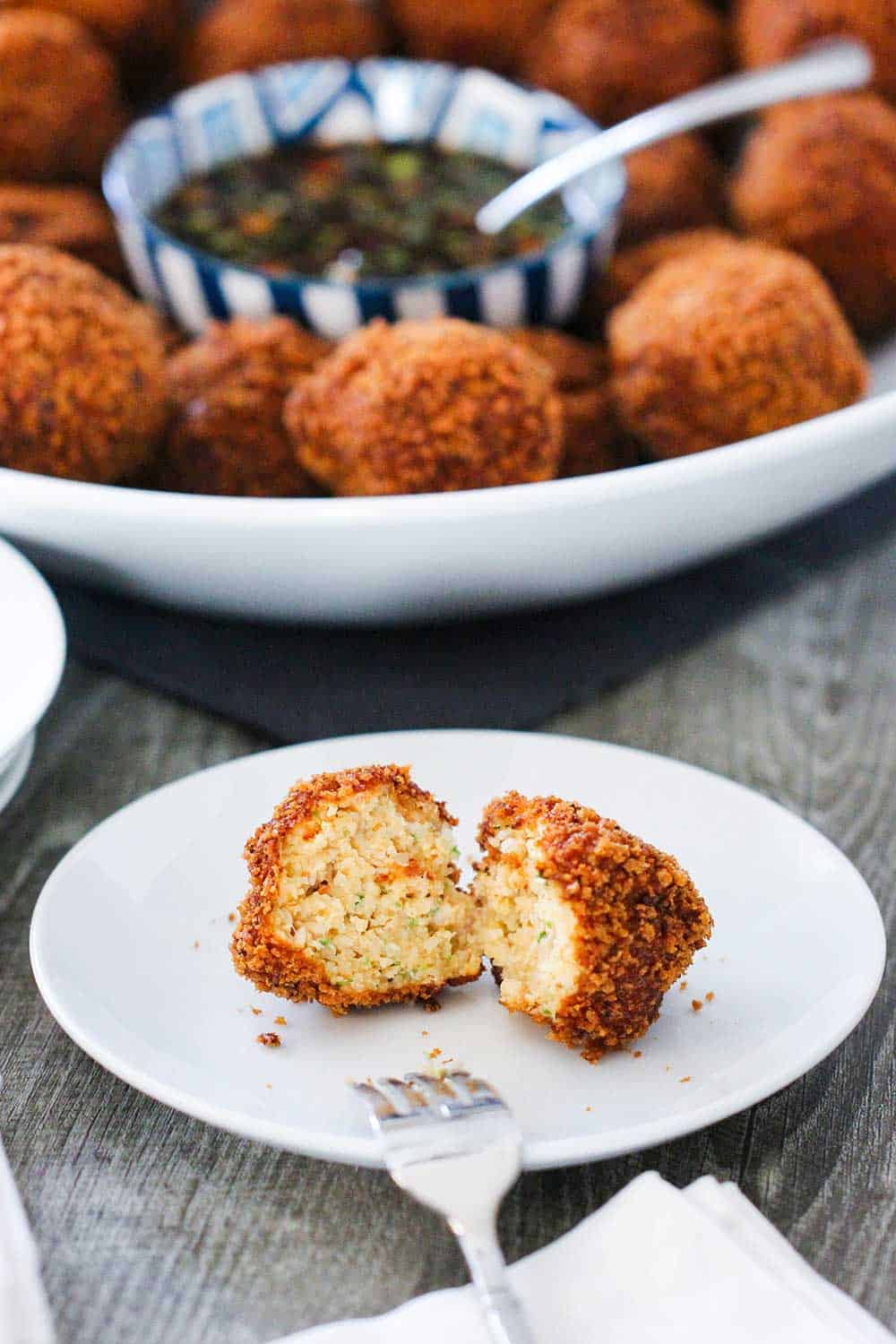 A fried shrimp ball on a white cocktail plate.