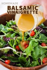 A hand pouring homemade balsamic vinaigrette from a jar onto a bowl filled with a green leaf salad.
