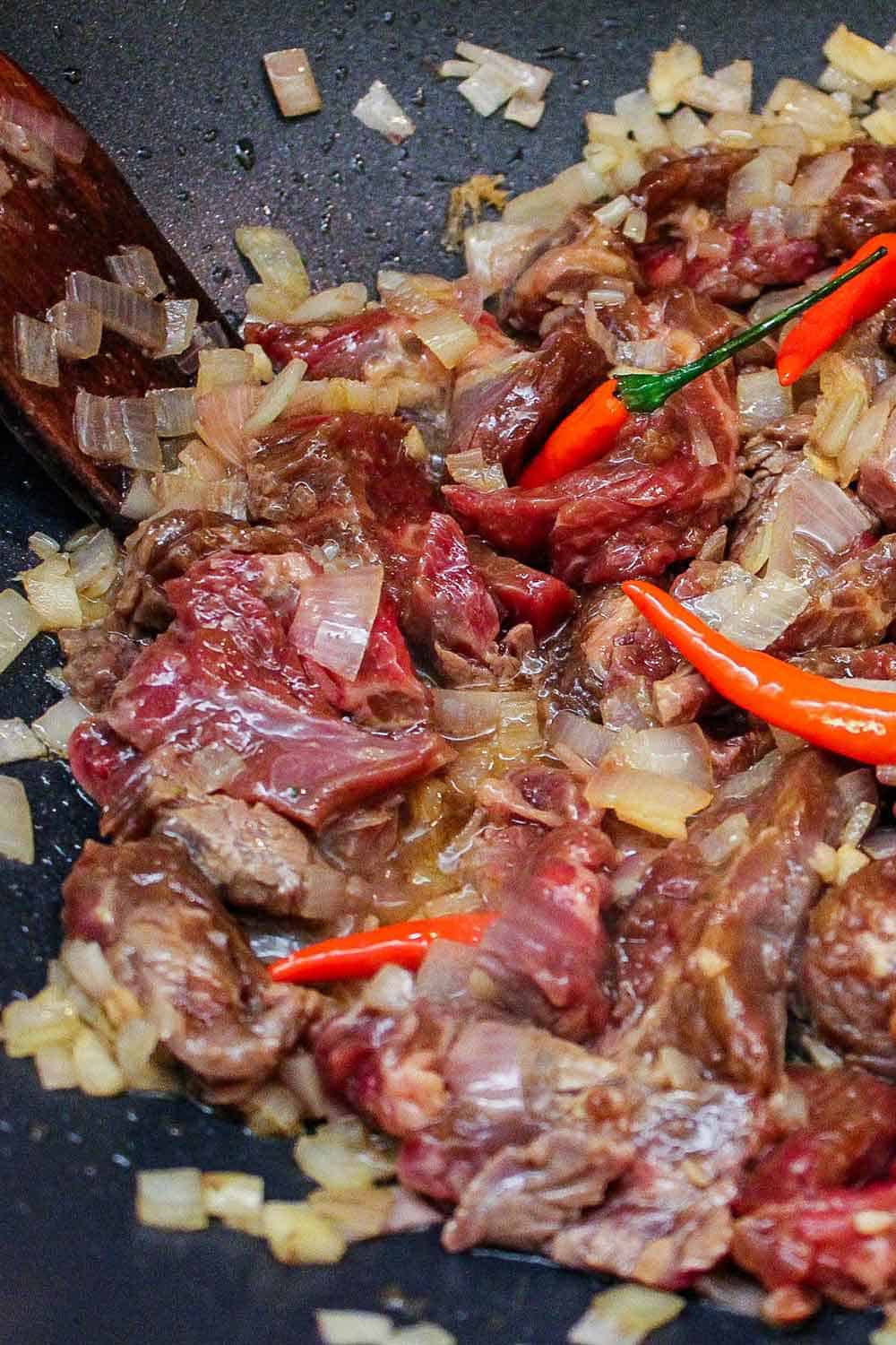 Cut the beef very thinly for stir-frying in a large wok.