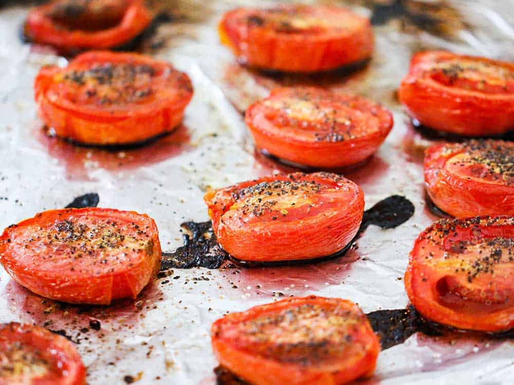 A baking sheet lined with foil with roasted tomatoes on it.