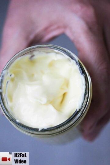 A hand holding a jar of Homemade Mayonnaise