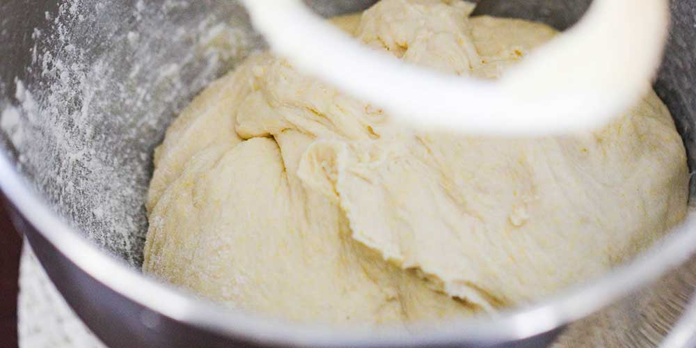 Pizza dough in the bowl of a stand mixer.