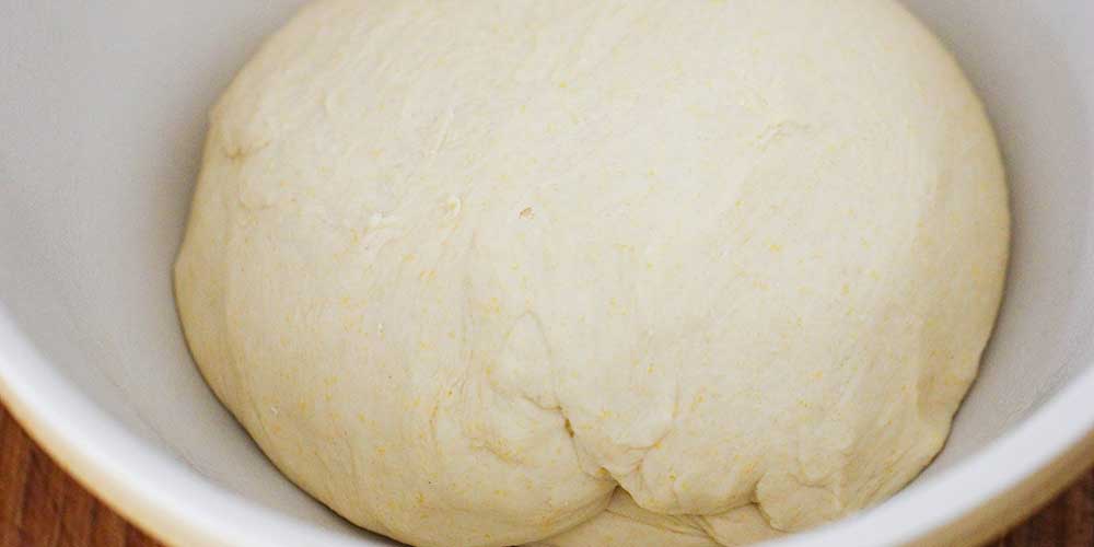 A ball of pizza dough in a ceramic bowl.
