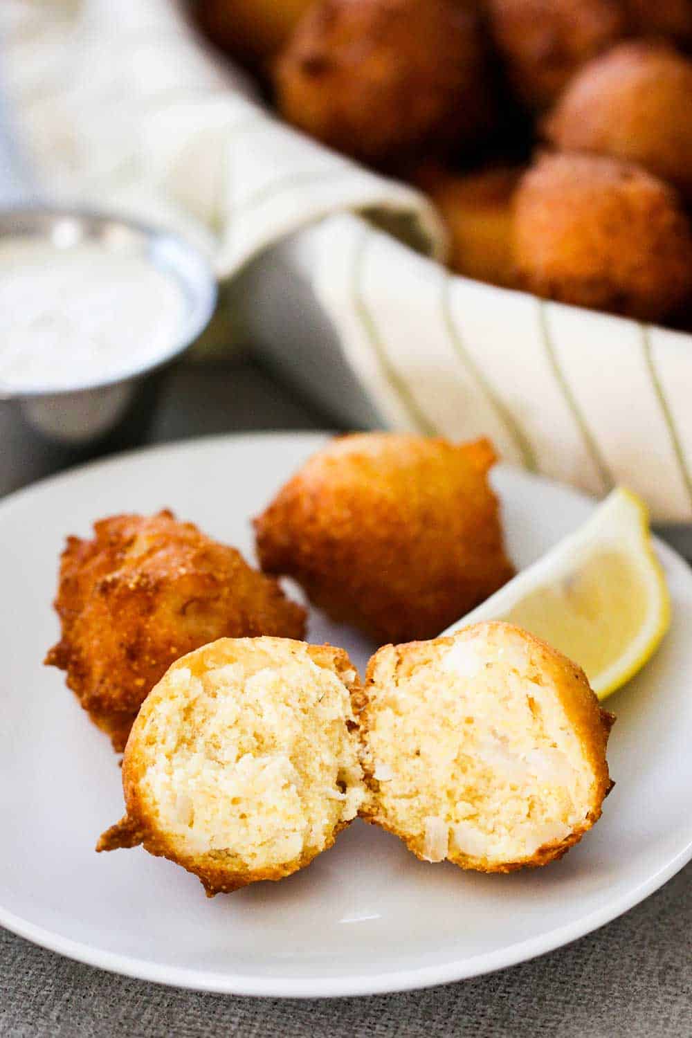 A small white plate holding freshly made Southern hush puppies that has been split open.