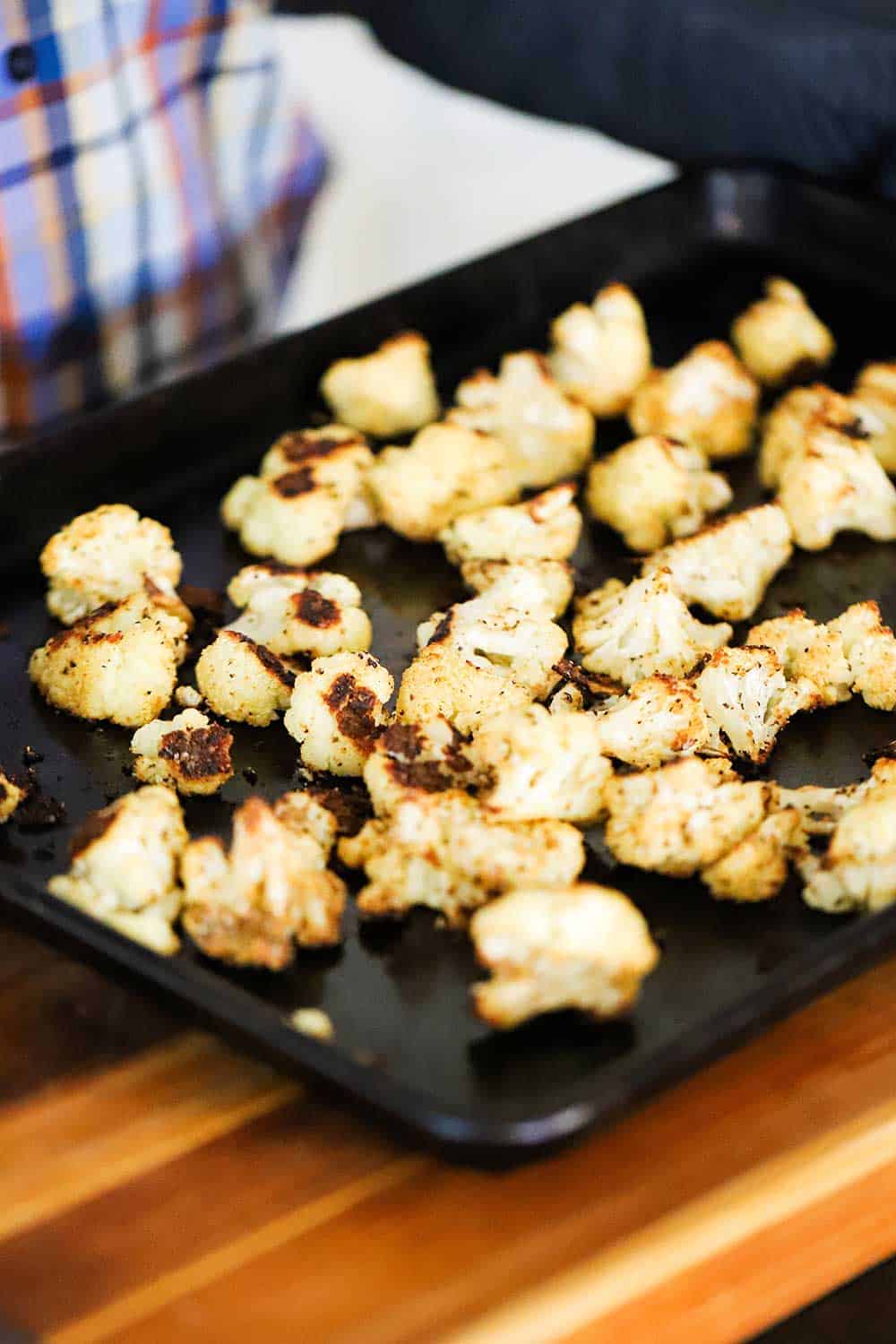 A baking pan filled with roasted cauliflower pieces that are slightly charred around the edges.
