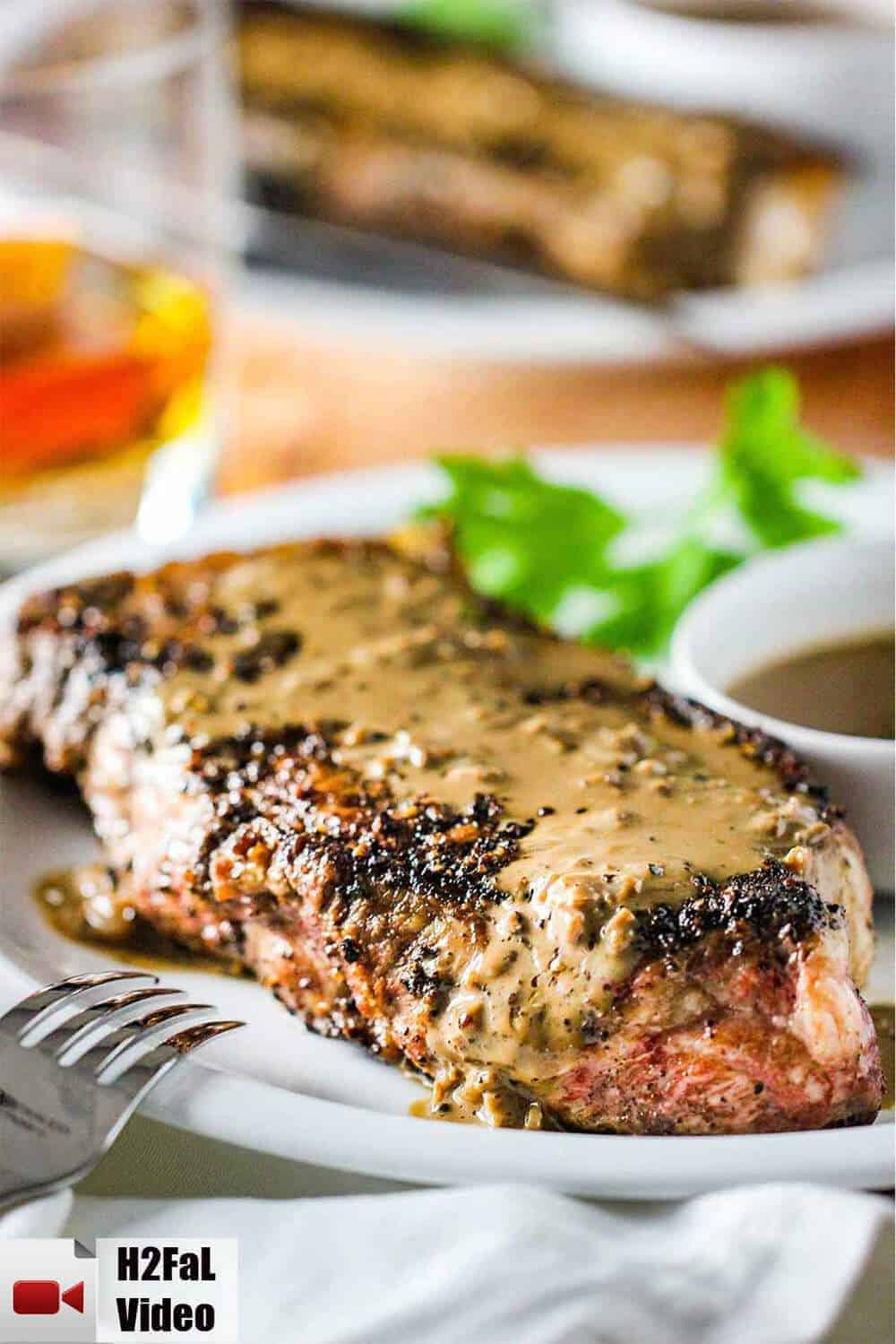 Steak au Poivre on a white plate with a fork nearby. 