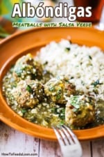 An orange dinner plate filled with four albondigas on a bed of salsa verde and a side of cilantro rice.