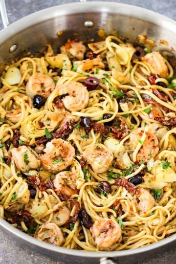 A large silver saucepan filled with Mediterranean pasta with shrimp.