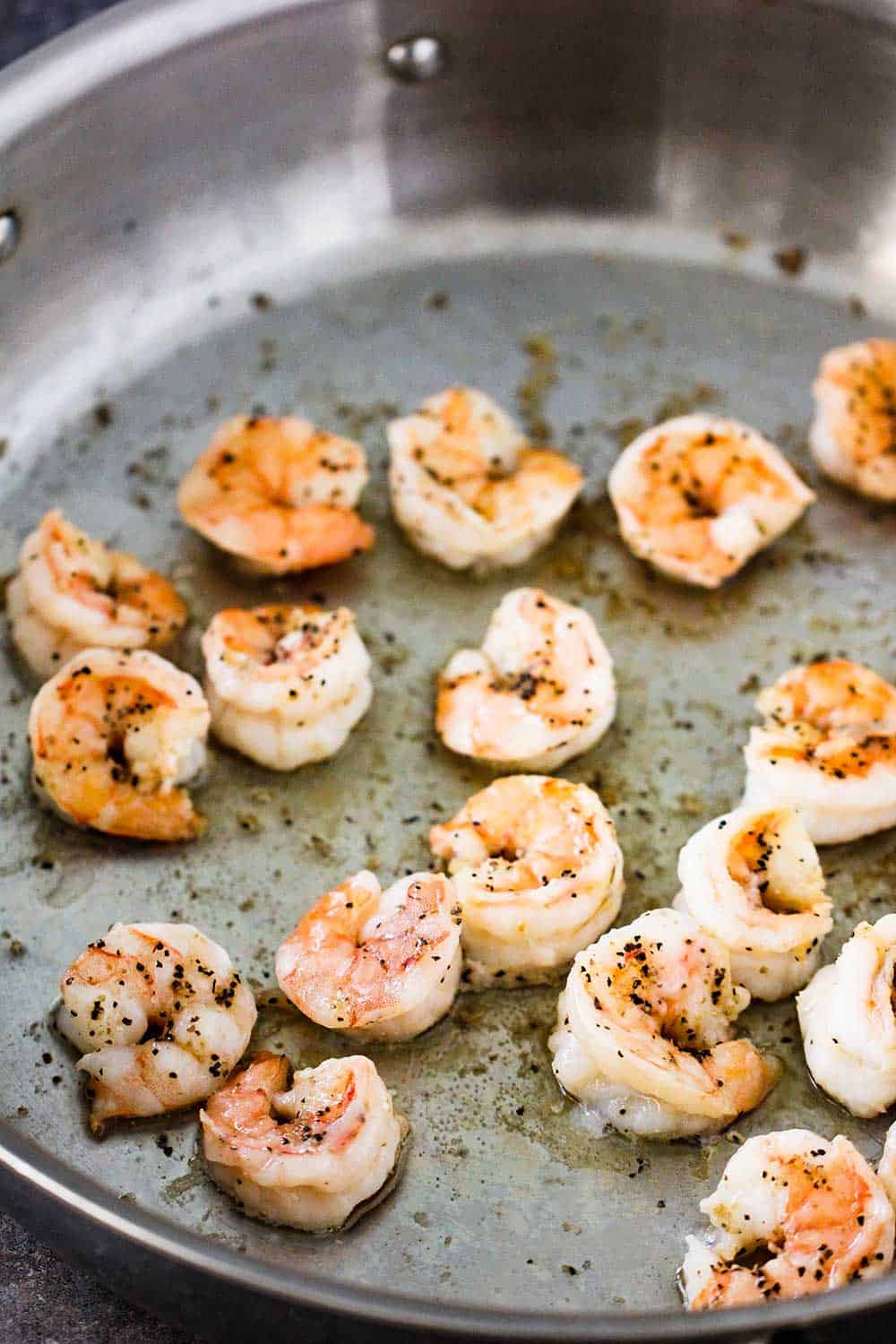 A large silver saucepan filled with sautéed shrimp.