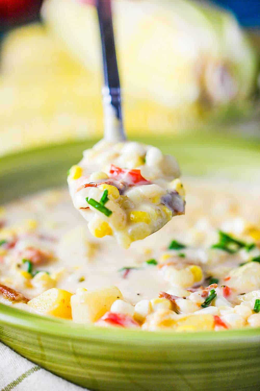A spoon holding a spoonful of farm fresh corn chowder.