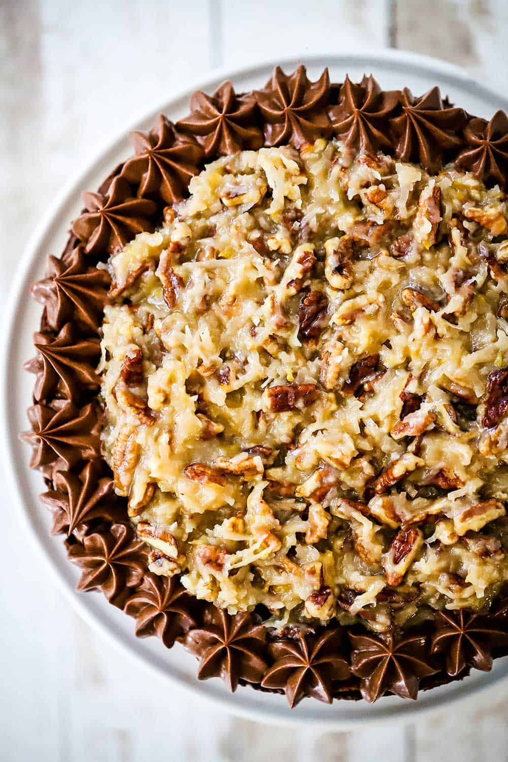 The top of a German chocolate cake covered with coconut pecan frosting and lined with chocolate frosting.