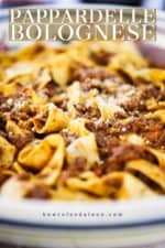 A close-up view of a large Italian pasta bowl filled with homemade pappardelle bolognese.