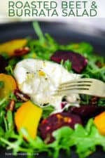 A fork breaking open a ball of burrata cheese sitting on top of sliced roasted beets and arugula salad.