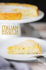 A slice of lemon ricotta cheesecake on a plate next to cake stand holding the cake.