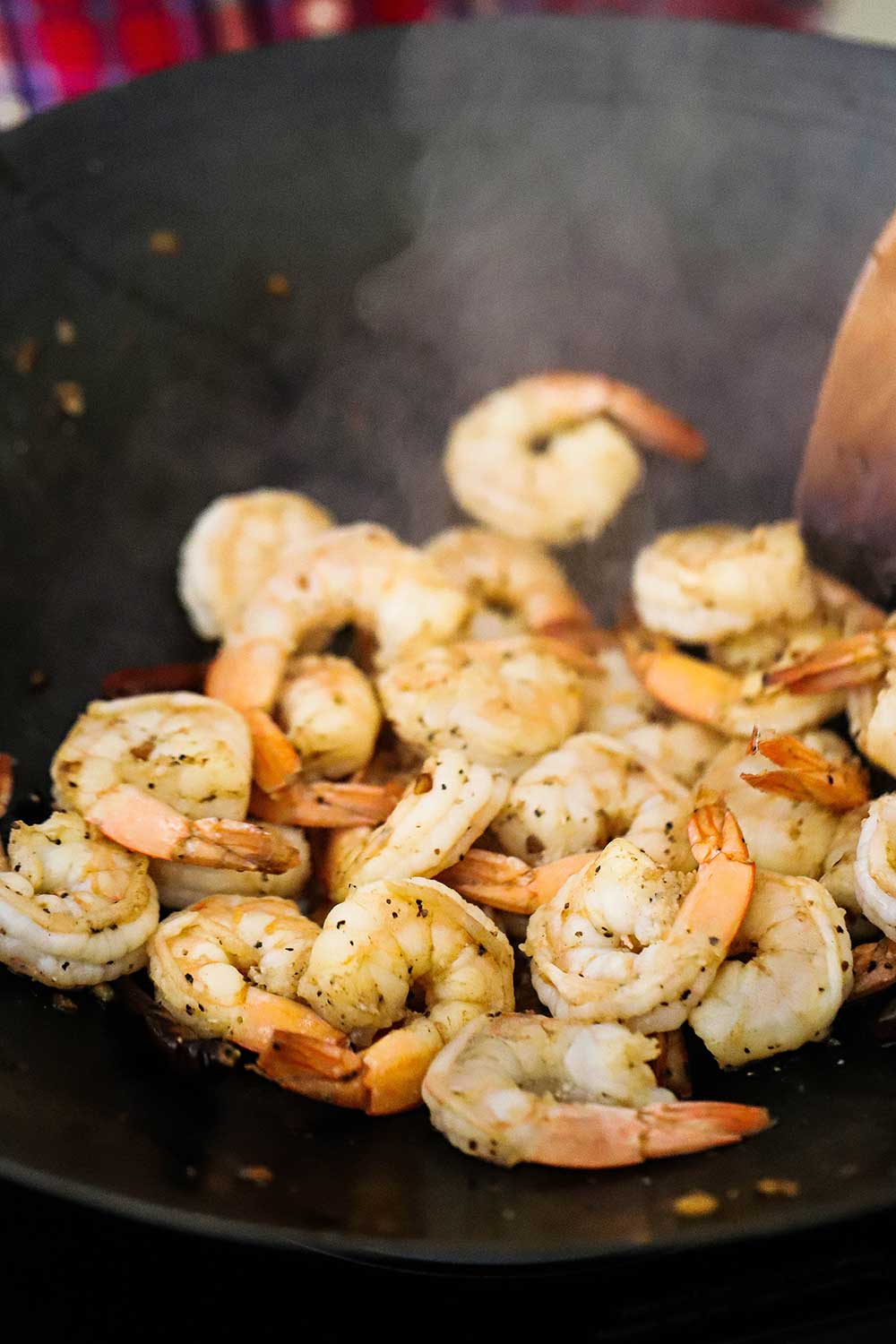 A wok filled with shrimp that has been sautéd in oil with garlic.