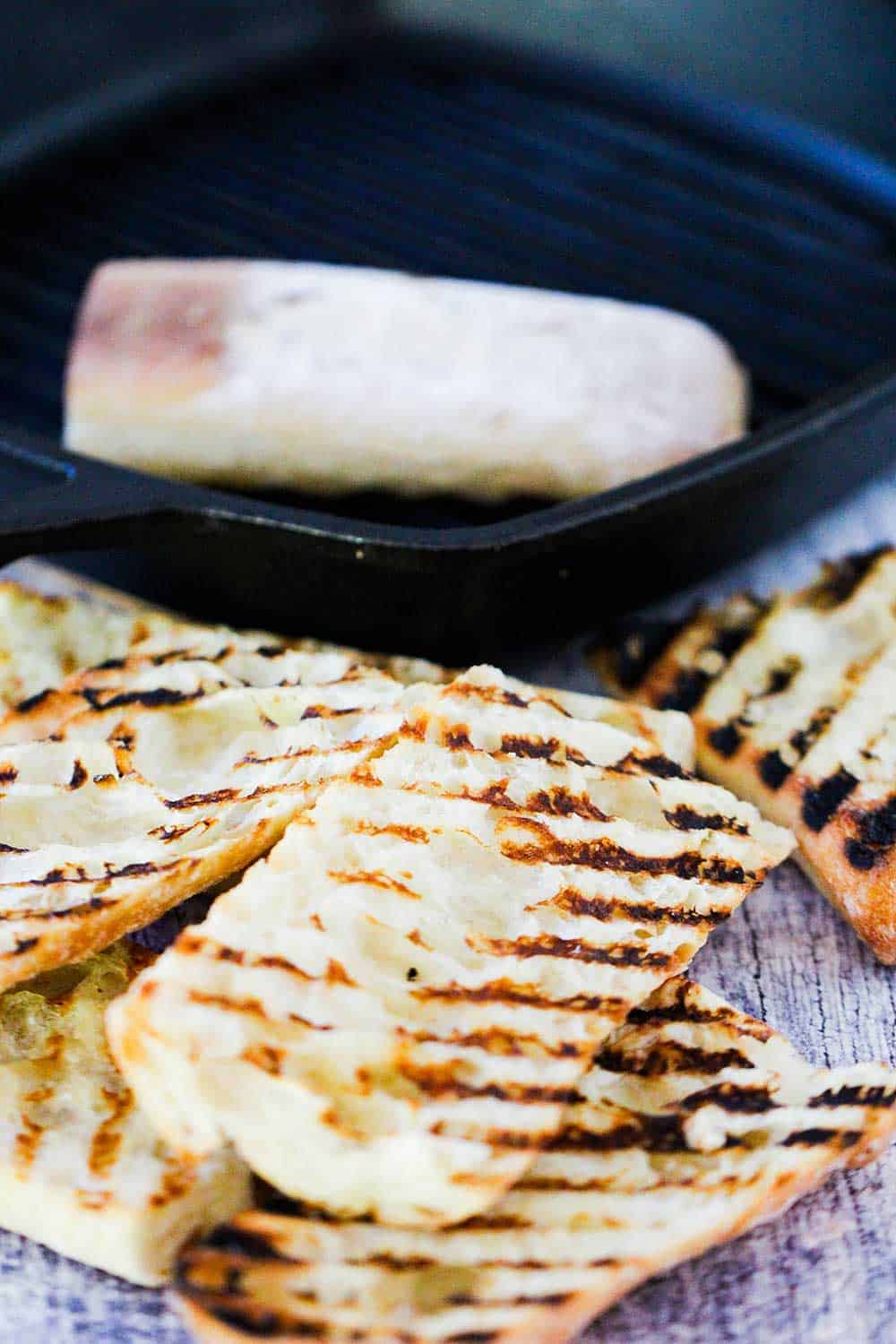 A stack of grilled bread next to a grill pan.