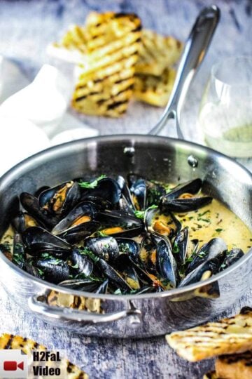 A large silver sauce pan with mussels and garlic and wine in it