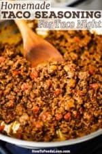 A large silver skillet filled with homemade beef taco meat made with homemade taco seasoning with a wooden spoon inserted off to the side.