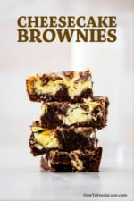 A stack of four square chocolate and cheesecake brownies on a white surface.