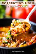 A spoon lifting out of a bowl filled with vegetable chili with black beans.