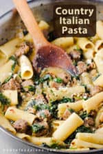 A large stainless steel skillet filled with Country Italian Pasta with a wooden spoon in it.