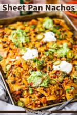 A straight-on view of sheet pan nachos topped with dollops of guacamole and sour cream.
