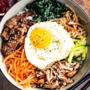 Authentic Bibimbap in a bowl with Korean BBQ sauce and chop sticks