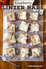 An overhead view of three rows of Linzer square sitting on parchment paper on a large wooden cutting board.