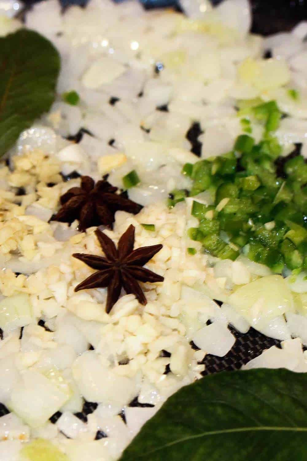 Onion, peppers and star anise cooking for authentic chicken curry