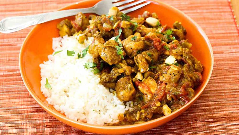 An orange bowl filled with basmati rice and authentic curry chicken