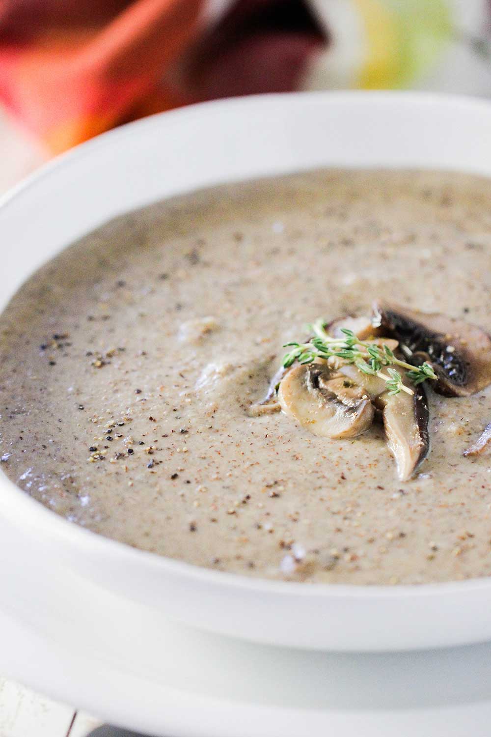 A close up view of a white soup bowl holding cream of mushroom soup with sautéed mushrooms on top.