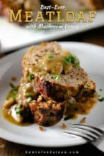 Two slices of meatloaf on a white plate with mushroom gravy poured over the top.