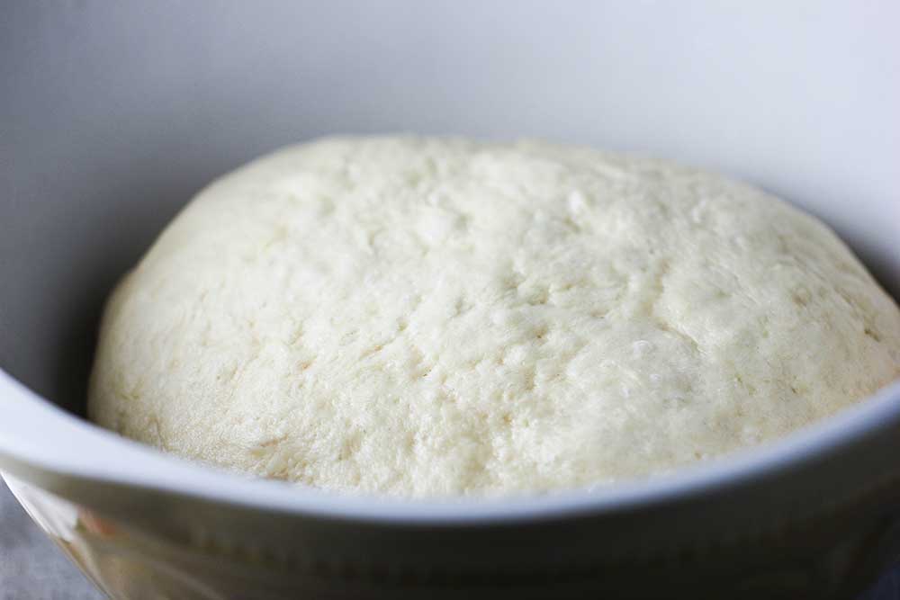 Risen dough in a large bowl for making jelly and custard doughnuts.