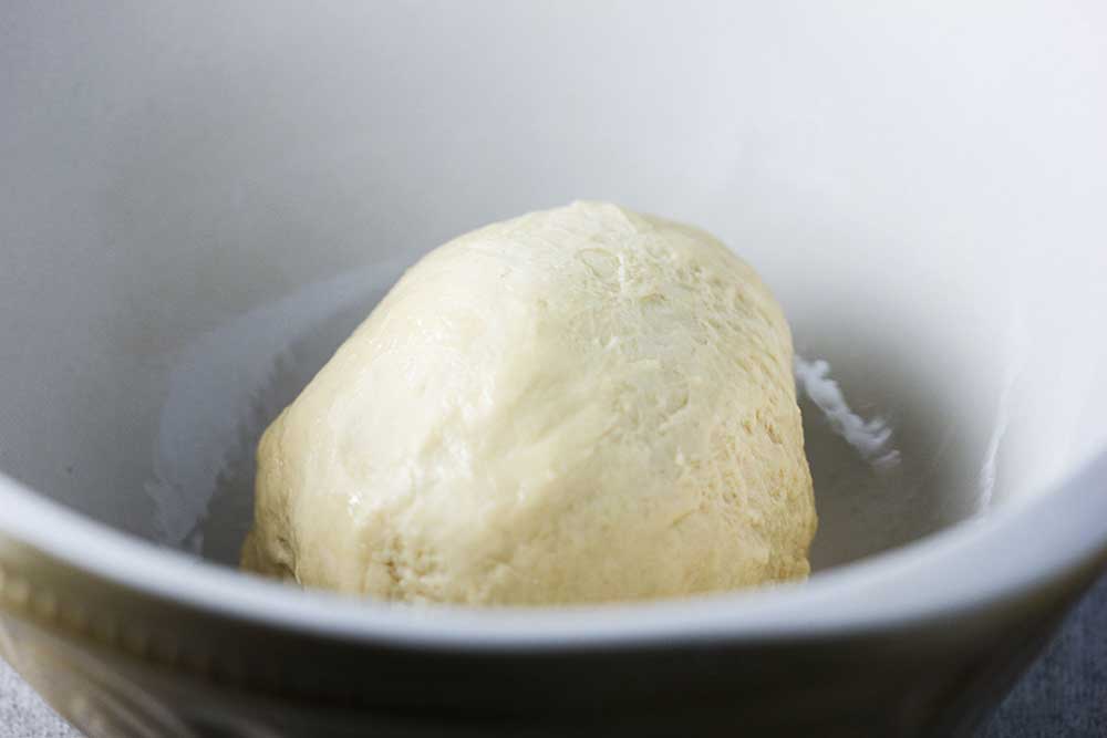 Doughnut dough in a large white bowl.