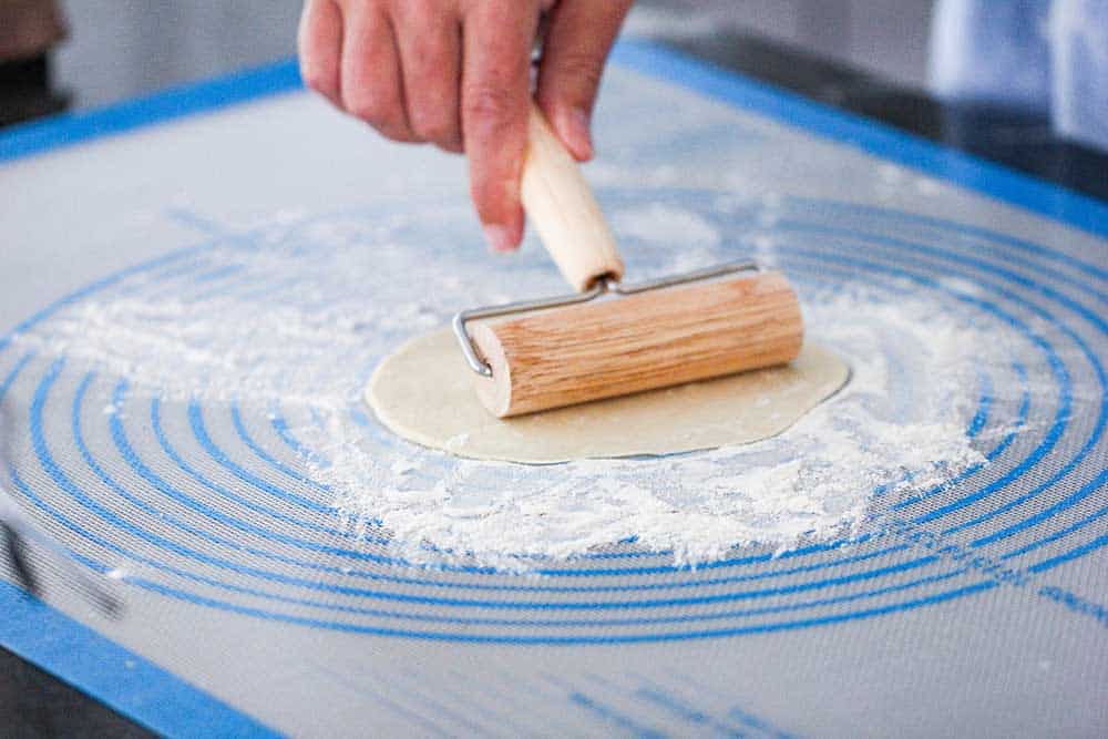 A pastry roller stretching out dough for homemade flour tortillas.