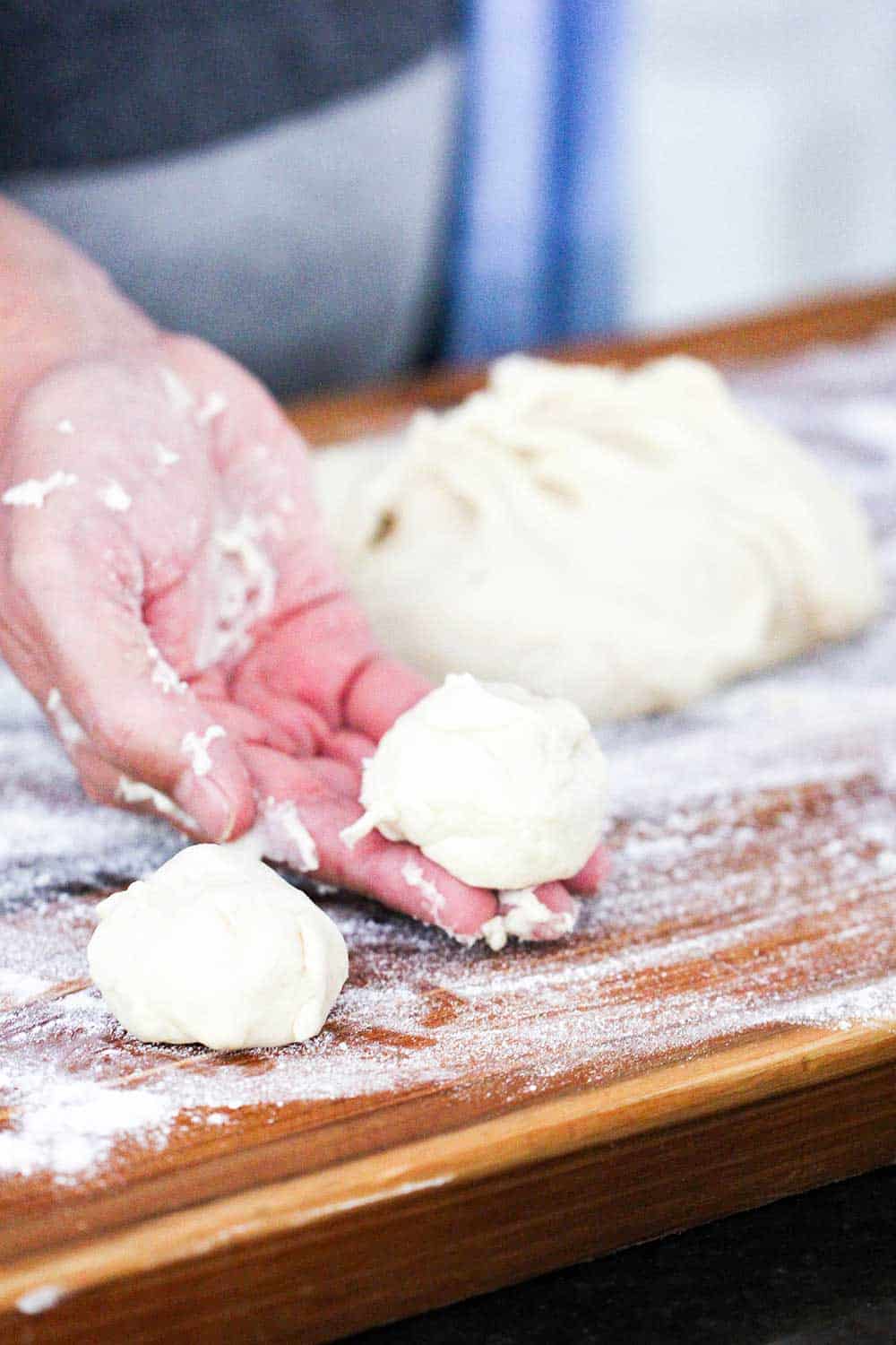 A hand holding a ball of dough for homemade flour tortillas.