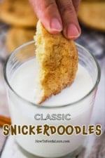 A hand dipping a snickerdoodle cookie that has been halved into a glass of milk.