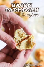 A person holding a parmesan bacon gourgere that has been split in two so the puffed interior is visible.