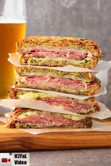 A stack of Italian-style Paninis with a beer in the background.