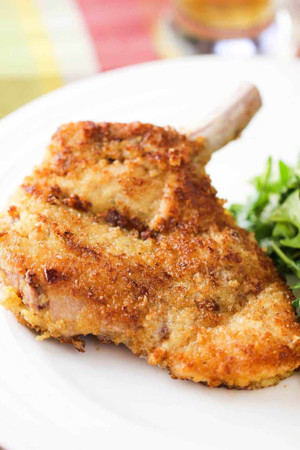 Pork Milanese chop on a white plate.