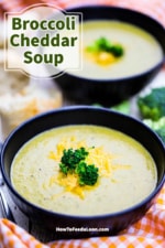 A straight-on view of two soup bowls filled with broccoli cheddar soup topped with shredded melty cheese and broccoli florets.