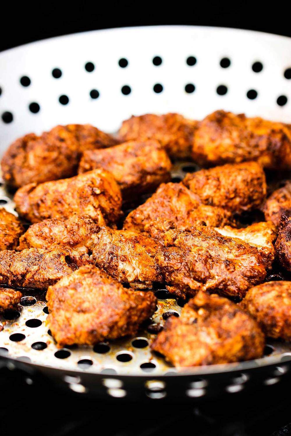 Blackened mahi-mahi pieces on a grill pan on a gas grill.