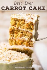 A metal spatula being used to lift up a large three-layered coconut cake with cream cheese icing and topped with toasted coconut flakes.