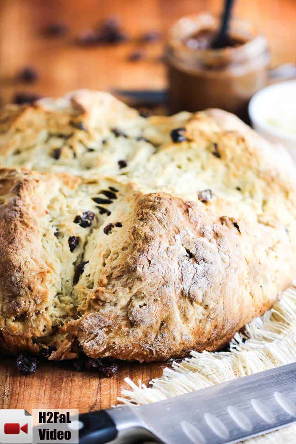 A loaf of Irish Soda Bread sitting on a carving board with a large knife next to it. 