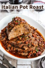 An Italian pot roast that has been sliced and is sitting in a large oval platter with a tomato and mushroom sauce all over it.