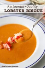 A close-up view of a person lifting a silver soup spoon that is filled with lobster bisque with a piece of fresh lobster meat on the spoon as well.